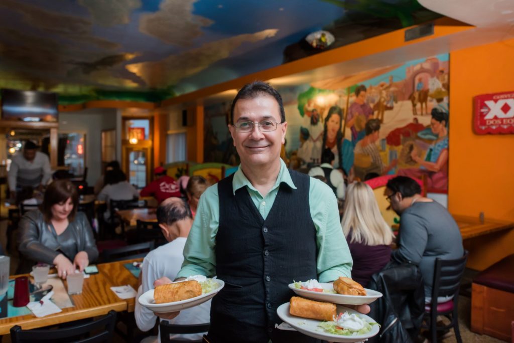 waiter serving chimichanga to diners